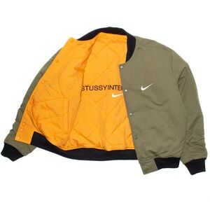 NIKE X STÜSSY REVERSIBLE VARSITY JACKET MEDIUM OLIVE / BRIGHT MANDARIN